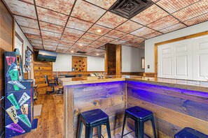 Un espace bar doté d’un comptoir en bois, de deux tabourets et d’un plafond orné d’un motif en réseau.