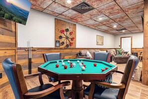 A pool table in a room with wooden walls and a ceiling with a grid pattern.