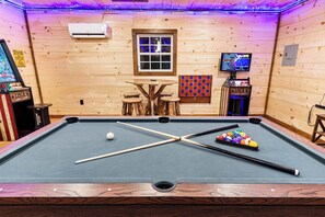 A pool table with balls, a pool cue, and a billiards rack.