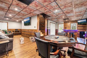 Una habitación espaciosa con una gran mesa de madera, asientos cómodos y un techo rústico.