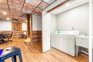 A laundry room with a washing machine, dryer, and a table with a bottle of laundry detergent.
