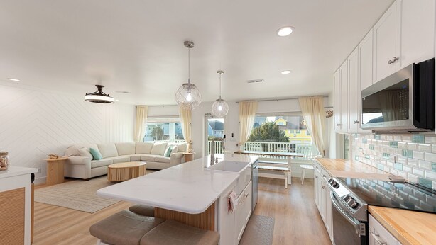 A modern kitchen with a central island, white cabinetry, and a large window offering a view of the outside.