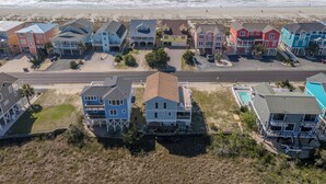 A coastal residential area with colorful houses, a beach, and a road.