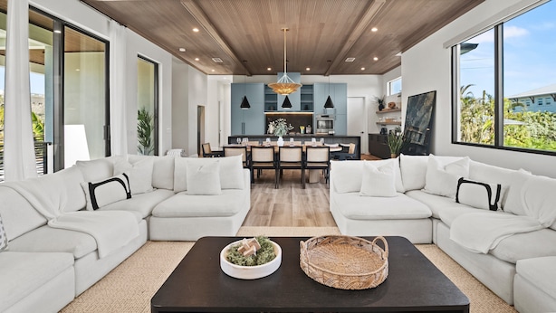 A modern living room with a sectional sofa, a coffee table, and a dining area with a kitchen in the background. - Experience the Ultimate in Coastal Luxury at A Point of Paradise (Sarasota)