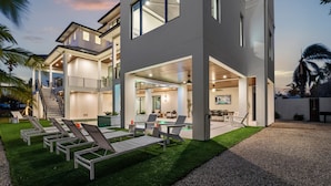 A modern two-story house with a covered outdoor area, a swimming pool, and a well-maintained lawn. - Experience the Ultimate in Coastal Luxury at A Point of Paradise (Sarasota)