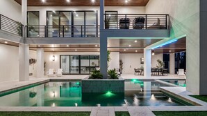 A modern multi-level residential building with a central swimming pool, outdoor seating, and a balcony with furniture. - Experience the Ultimate in Coastal Luxury at A Point of Paradise (Sarasota)