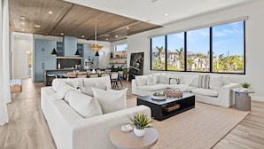 A spacious living area with a modern kitchen, large windows with a view, and a ceiling fan. - Experience the Ultimate in Coastal Luxury at A Point of Paradise (Sarasota)