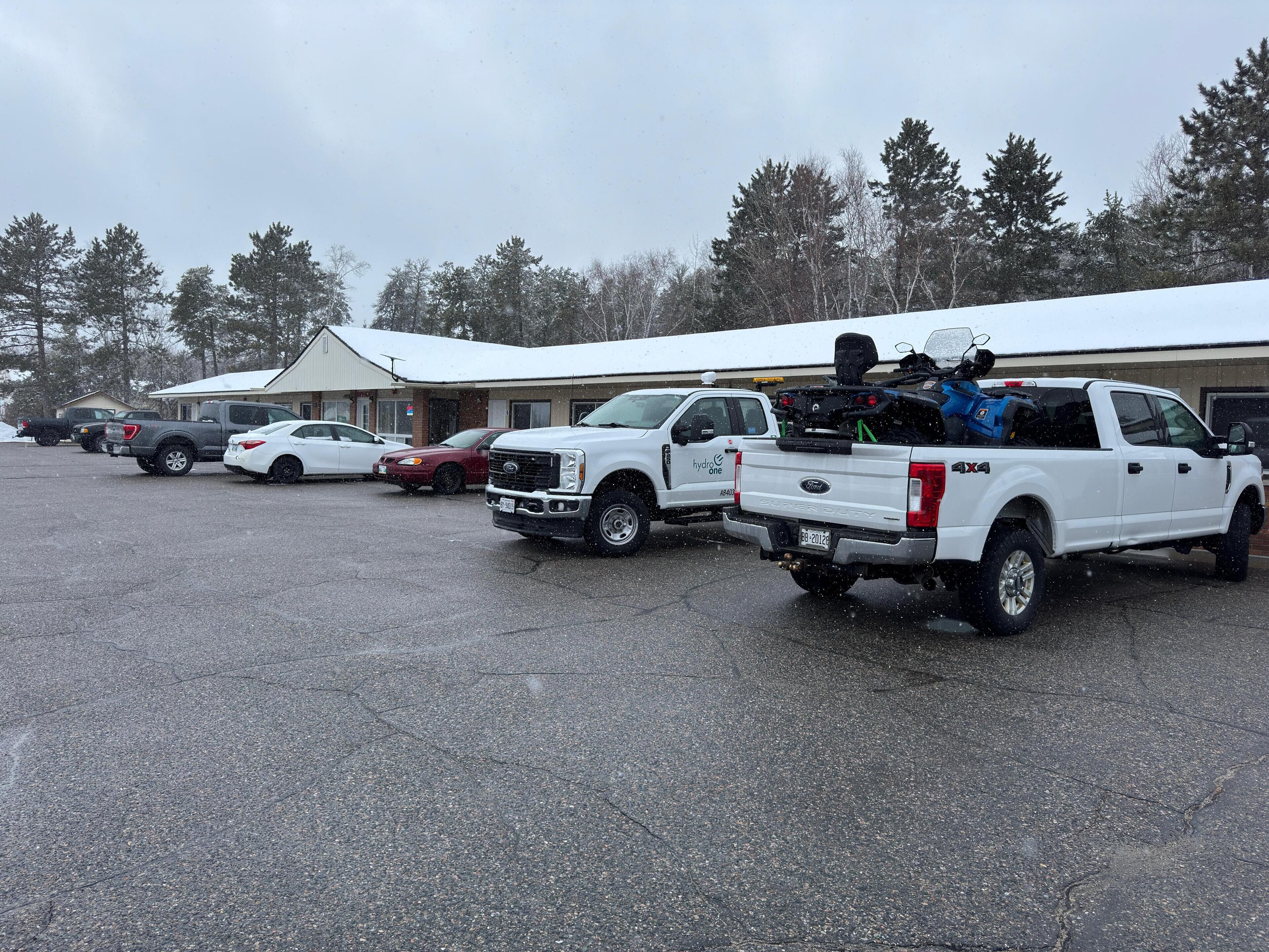 A parking lot with several vehicles, including a white pickup truck with a blue object on the back.