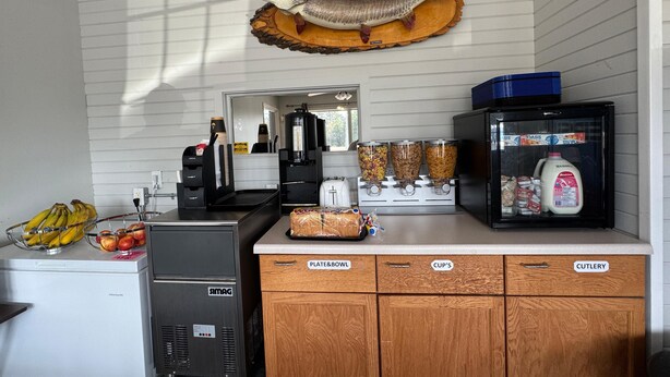 Une cuisine équipée d’un réfrigérateur, d’une machine à café, d’un présentoir à pain et d’un réfrigérateur à lait.