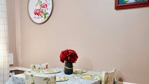 A dining area with a round table covered in a floral tablecloth, surrounded by chairs with floral upholstery. - Cozy, gallery-inspired stay, 5min to Fort Liberty (Fayetteville)