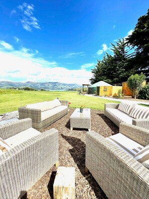An outdoor seating area with wicker furniture and a view of mountains. - Big Sky Retreat - beautiful house and glamping yurts overlooking Akaroa Harbour. (French Farm)