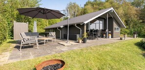 A patio with outdoor furniture, a grill, and a large umbrella.