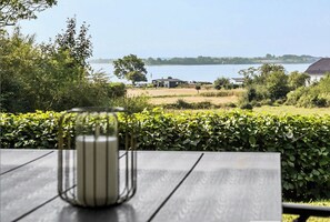 A table with a striped vase, a view of a lake, and a distant building.
