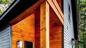 A wooden cabin with a porch, a door, and a potted plant.