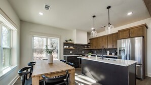A modern kitchen with a central island, dark cabinetry, and stainless steel appliances.