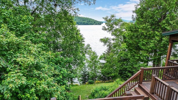 A wooden deck overlooking a lake with lush greenery and a clear view of the water.