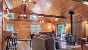 A spacious cabin with a large living area featuring a sofa, a fireplace, and a dining area with bar stools.