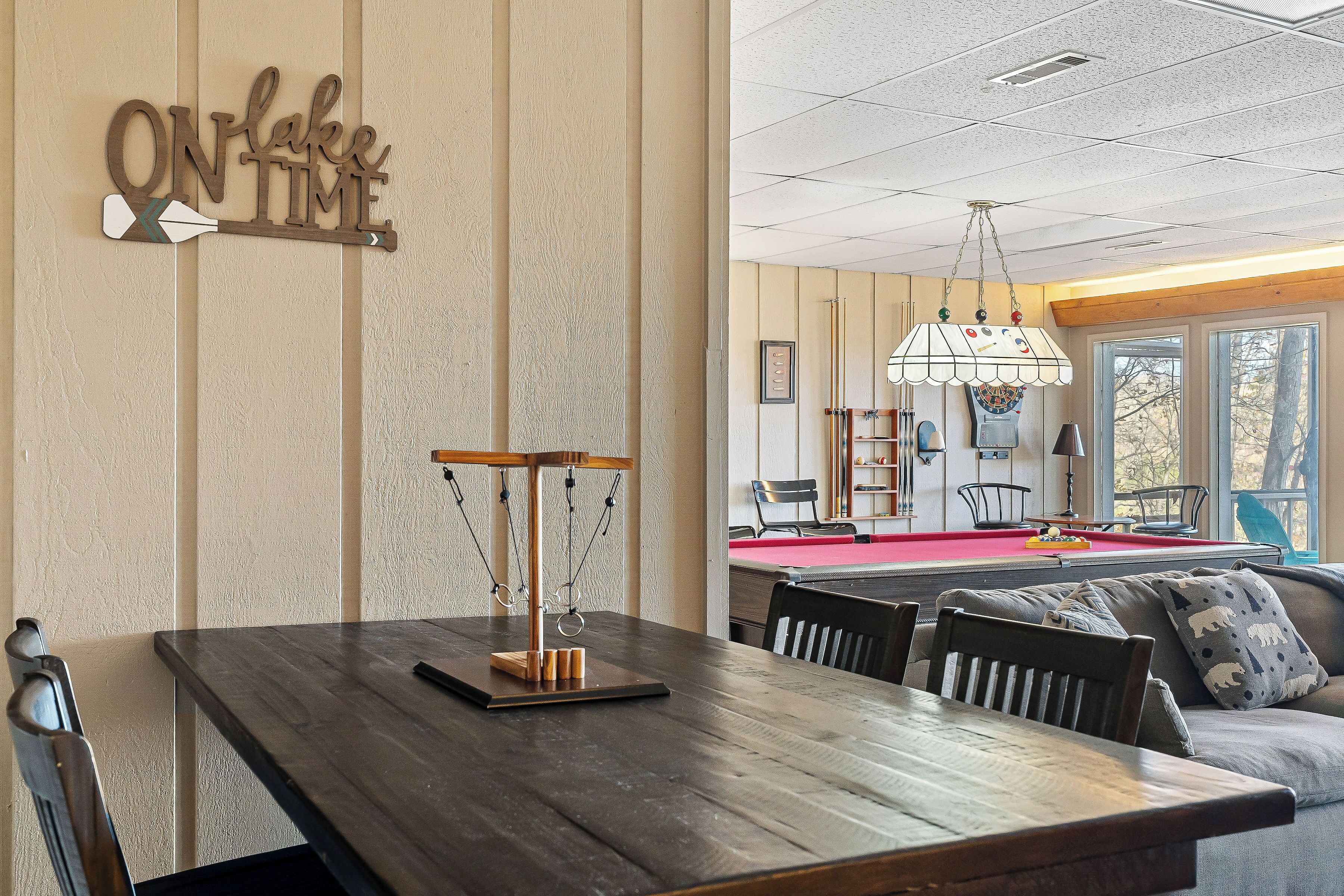 Un coin repas avec une table en bois, des chaises et un panneau fixé au mur sur lequel on peut lire : « À L’HEURE ».