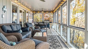 A covered porch with wicker furniture, large windows, and a ceiling fan.