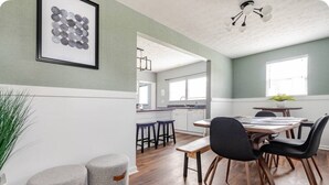 Una cocina moderna con armarios blancos, encimera de madera y comedor con mesa de madera y sillas negras.