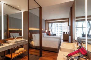 A modern hotel room with a large bed, a separate bathroom with a sink and mirror, and a view of the city through large windows. - 采寓halo house (Taichung)