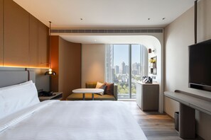 A modern hotel room with a large bed, a seating area, a TV, and a city view. - 采寓halo house (Taichung)