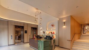 Un moderno vestíbulo de hotel con mostrador de recepción, reloj digital, escalera y piso con diseño.