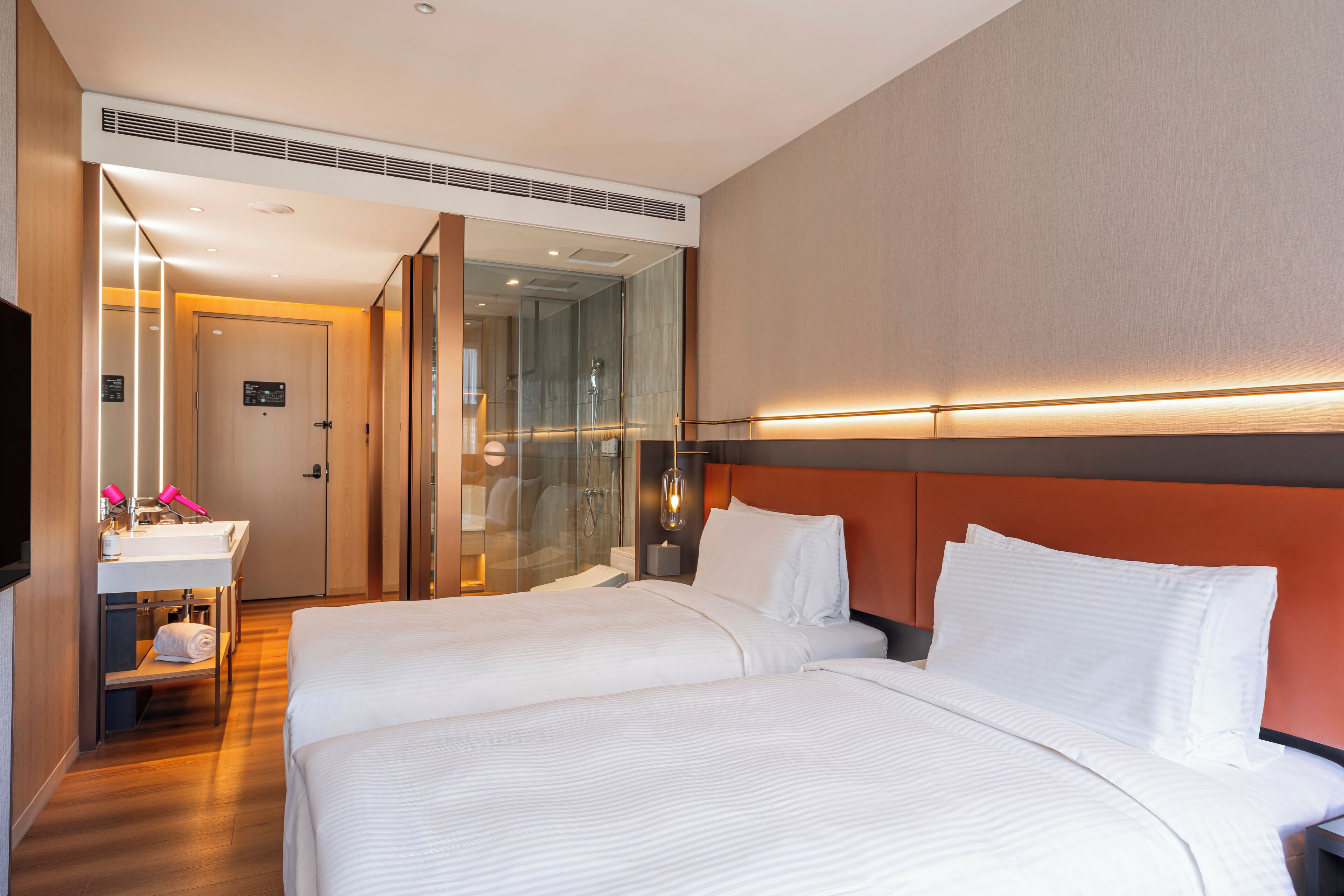 A hotel room with two beds, a bathroom, and a television.
