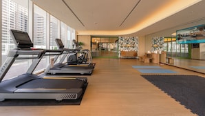 A modern gym with treadmills, stationary bikes, and a large TV screen. - 采寓halo house (Taichung)