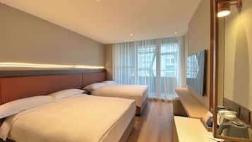 A hotel room with two beds, a large mirror, and a view of the city through sheer curtains.