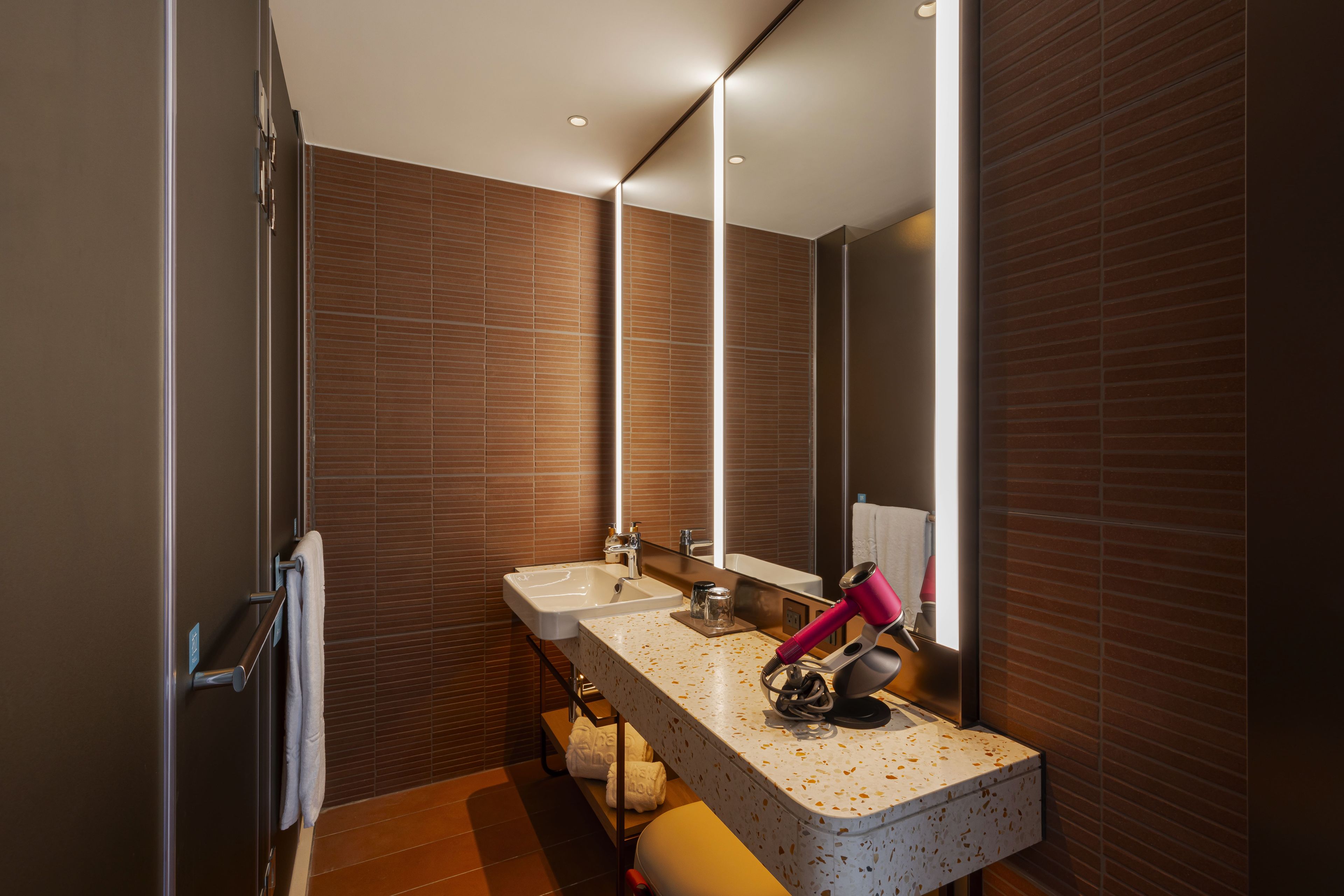 A modern bathroom with two sinks, a mirror, and a towel rack.