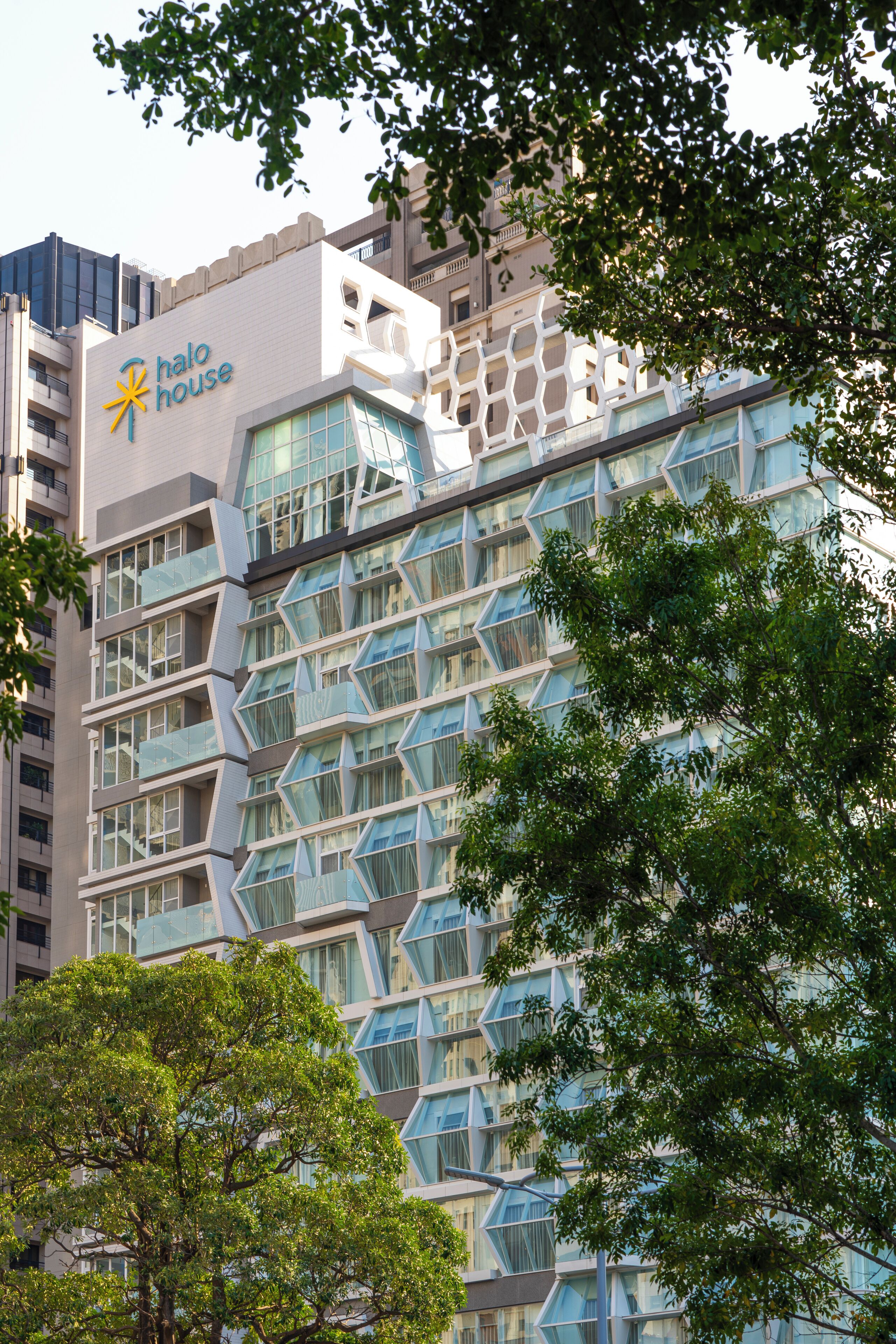 A modern building with a 'halo house' sign, featuring a unique geometric facade and large windows.