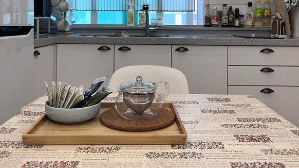 Une cuisine moderne avec des meubles blancs, un four à micro-ondes et une fenêtre équipée de stores.