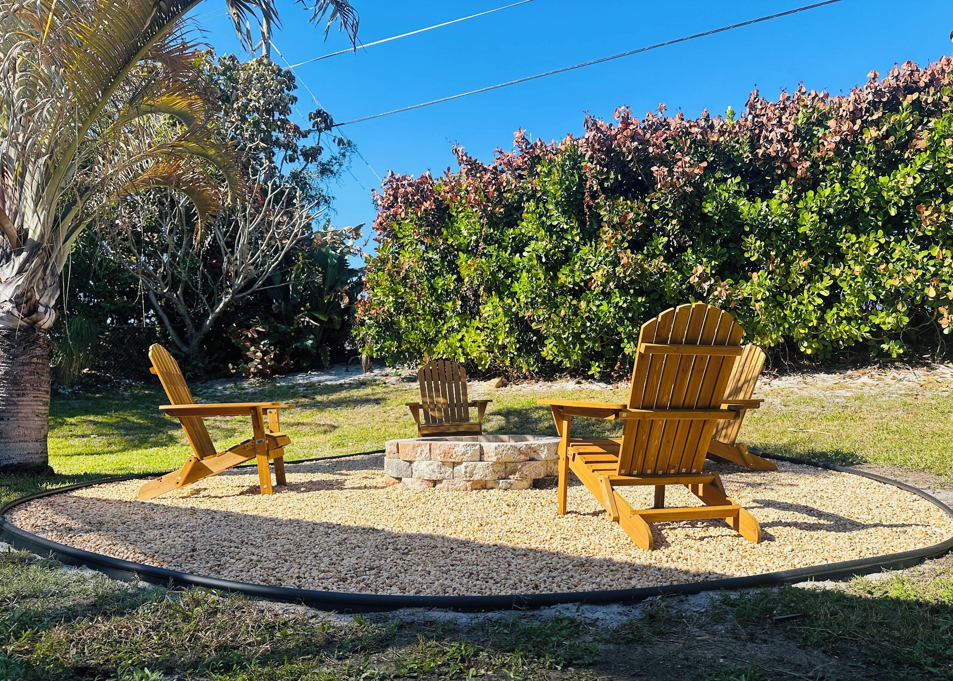 A patio area with Adirondack chairs, a small table, and a fire pit surrounded by gravel.