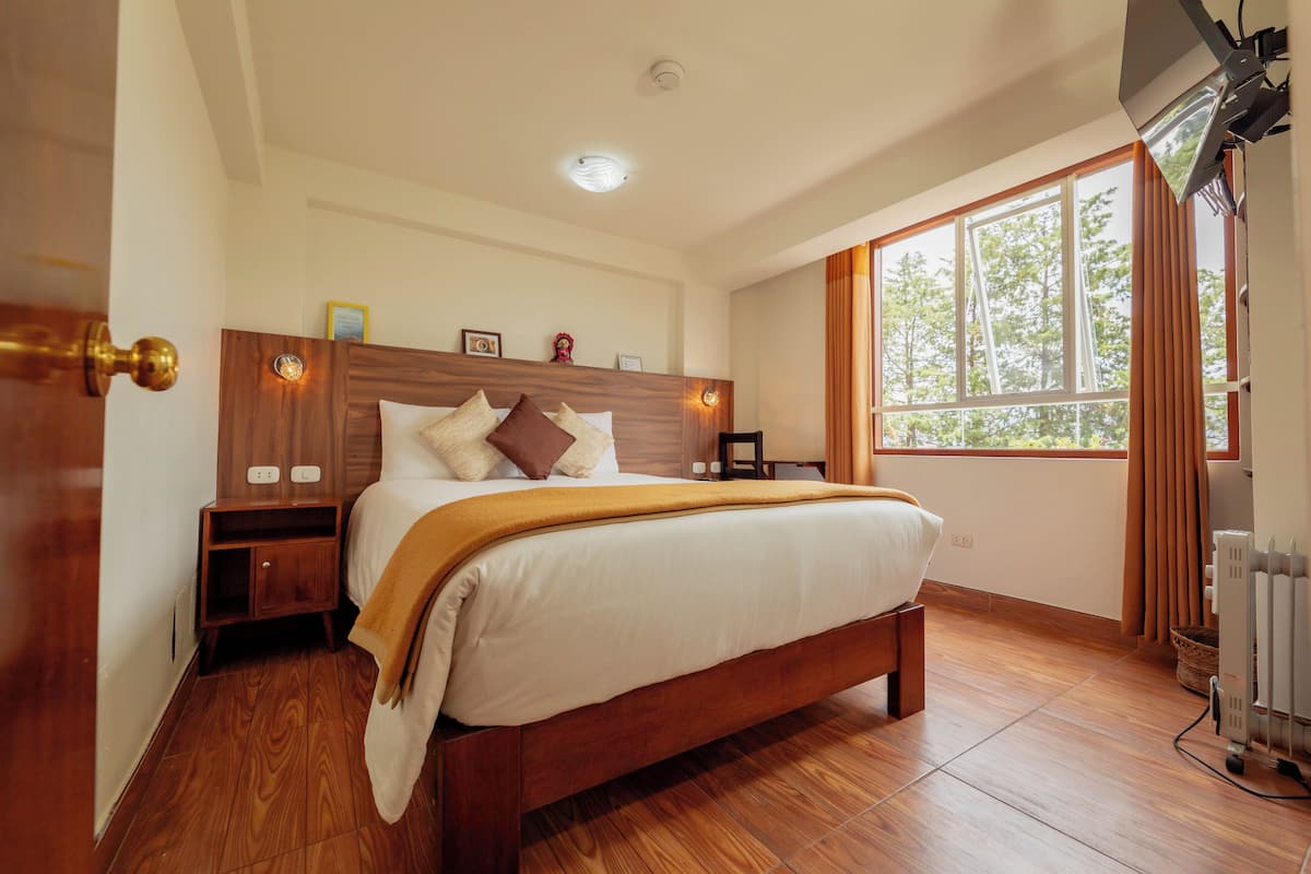 A bedroom with a wooden bed, a nightstand, a window with curtains, and a ceiling light.