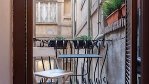 A small outdoor balcony with a metal railing, a white folding chair, and a table. - GuestHost - Charming Apartment near Spanish Steps (Rome)