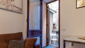 A living room with a brown sofa, a white table, and a chair. - GuestHost - Charming Apartment near Spanish Steps (Rome)