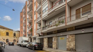 A multi-story residential building with balconies, parked cars, and a closed garage door.