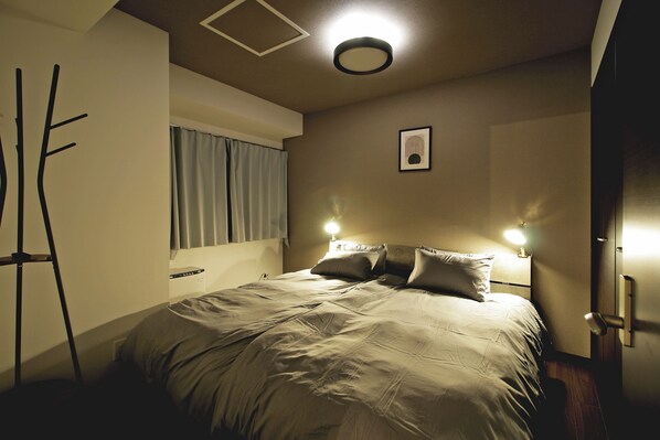 A bedroom with a bed, a nightstand, a lamp, and a window with curtains.
