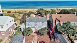 Una zona residencial costera con una casa destacada de fachada de piedra, tejado rojo y un jardín pequeño en el patio delantero.