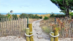 Un sendero que lleva a una playa con una valla de madera y un comedero para pájaros.