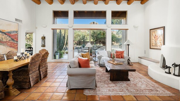 Un amplio salón con techo de madera, ventanas grandes, una mesa de comedor con sillas y una chimenea.