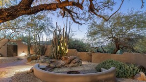 Un jardín desértico con cactus, una jardinera circular y un sendero de ladrillo.
