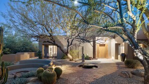Un jardín desértico con cactus, un sendero de ladrillo y un edificio con puerta de madera.