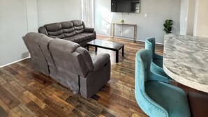 A modern living room with a sectional sofa, a coffee table, and a dining area with a marble table. - Newly updated home on Spruce St (Mason)