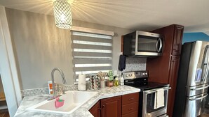 A modern kitchen with a marble countertop, wooden cabinets, stainless steel appliances, and a wooden herringbone floor. - Newly updated home on Spruce St (Mason)