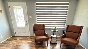 A room with two brown leather armchairs, a small round table with a plant, and a door with a window. - Newly updated home on Spruce St (Mason)