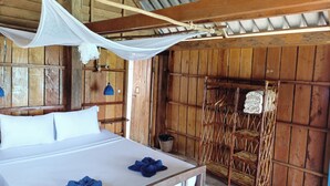 Una habitación de madera con una cama, una silla colgante y una mosquitera.