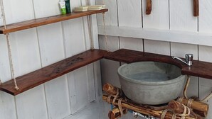 Un baño rústico con estantes de madera, suelo de baldosas de piedra y un lavabo grande.