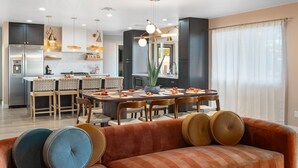 Een moderne keuken met donkere kastjes, een centraal eiland en hanglampen.